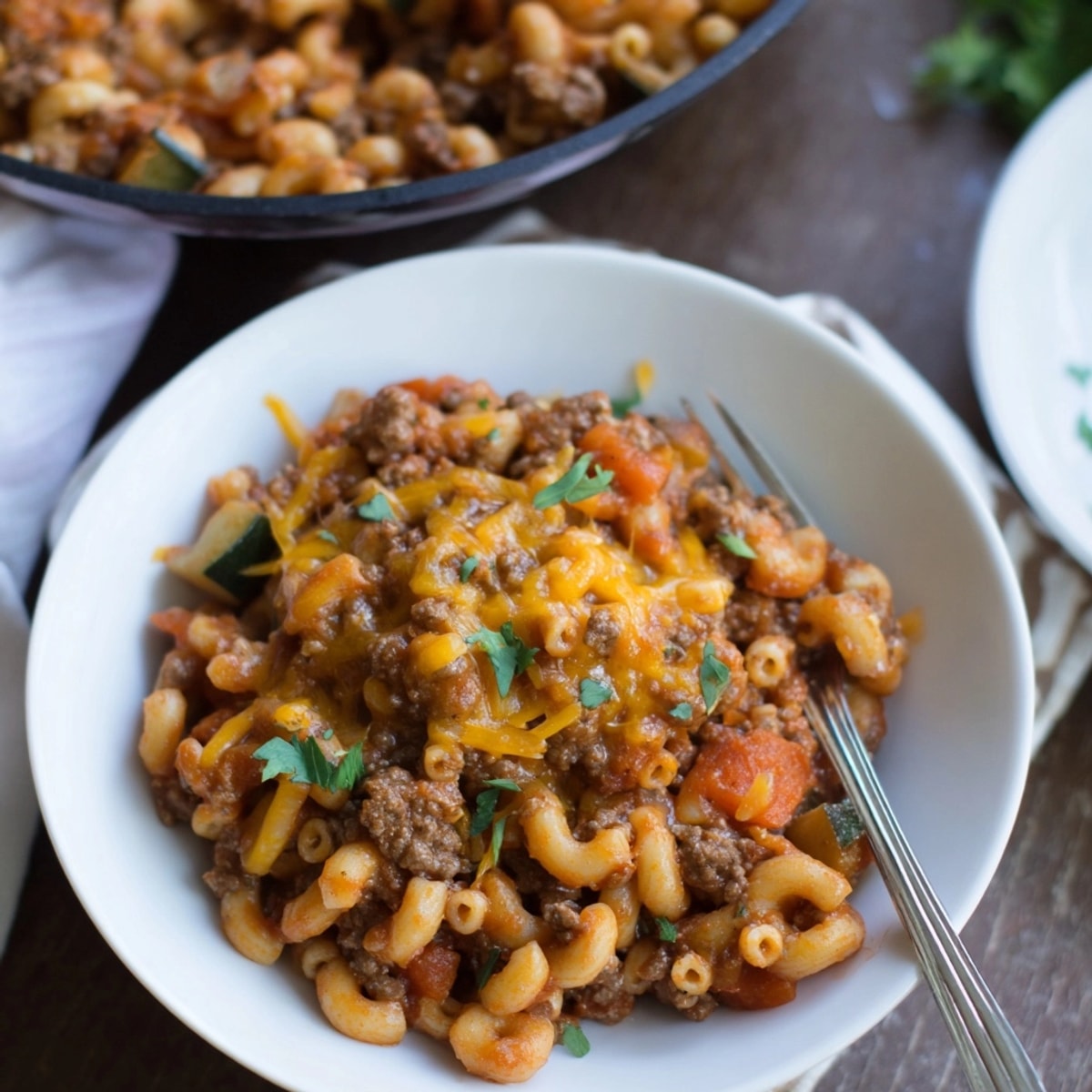 A steamy bowl of Healthier One-Pot Hamburger Helper, cheesy and topped with parsley.