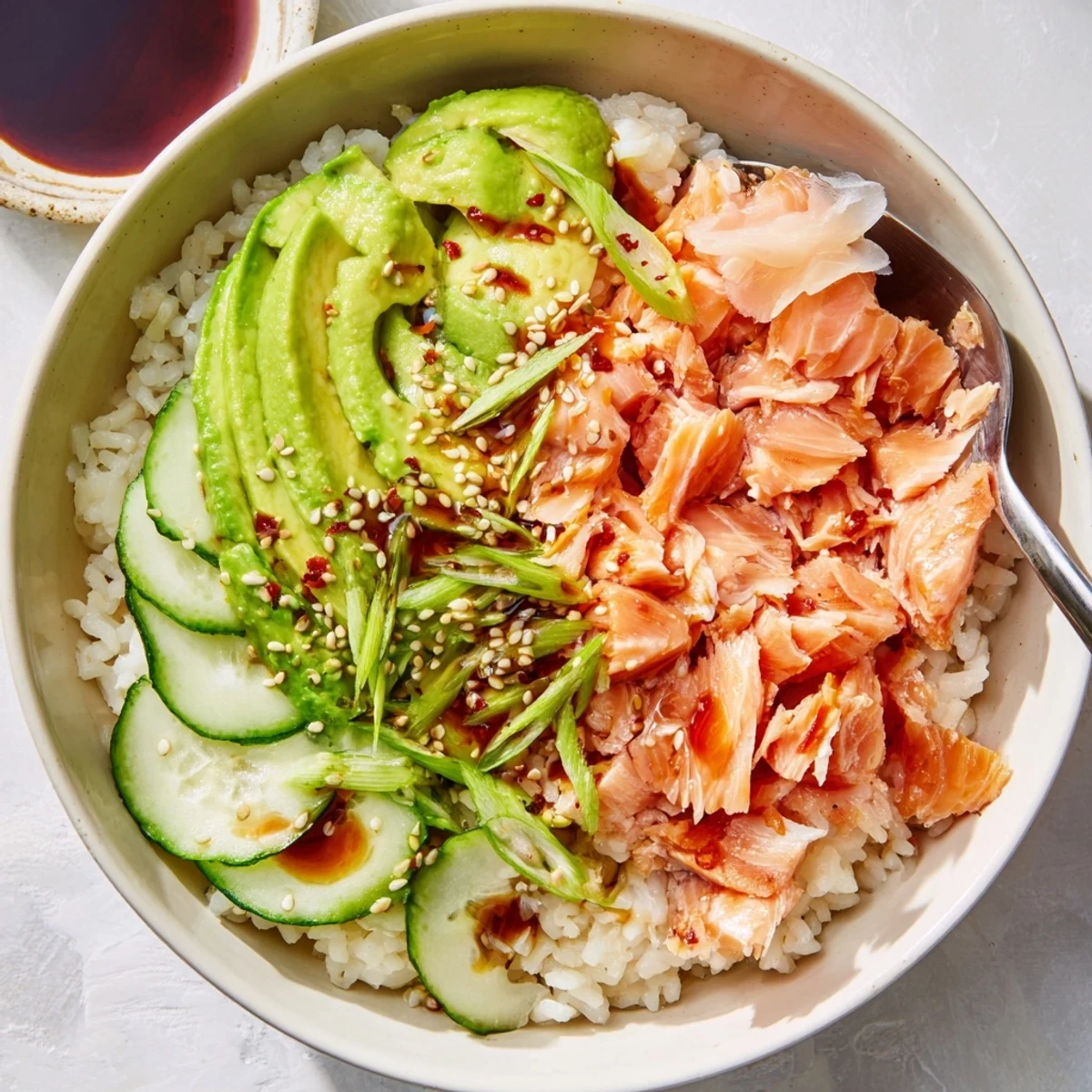Flavorful salmon and rice bowl featuring vibrant toppings like pickled ginger and scallions.