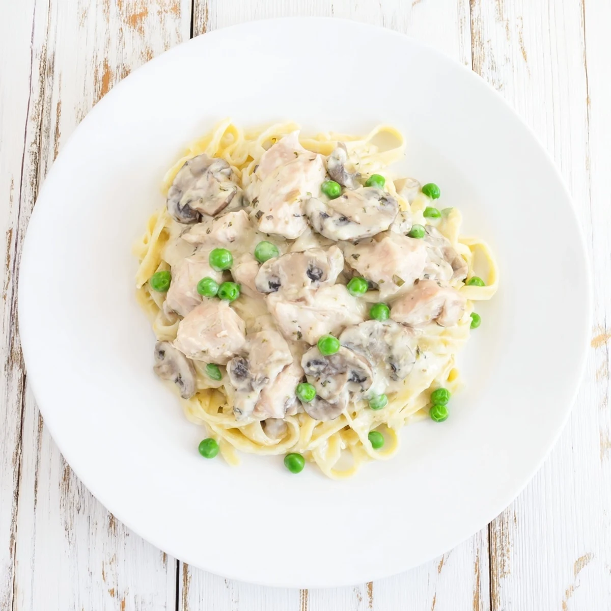 A warm bowl of Creamy Chicken Alfredo Slow-Cooker Dump Meal, ready to serve over fettuccine noodles.