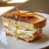 Golden-brown Brie, Apple & Honey Christmas Candle Grilled Cheese, oozing melted cheese with apple slices.