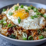 Savory kimchi fried rice bowl topped with a sunny-side-up egg, boasting vibrant flavors.