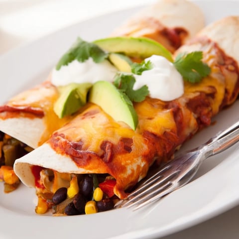 Vibrant Farmers Market Vegetarian Enchiladas topped with melted cheese and fresh avocado slices.  