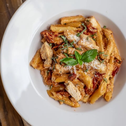 Creamy Tomato Basil Chicken Pasta in a skillet, glistening with rich tomato sauce and fresh basil.