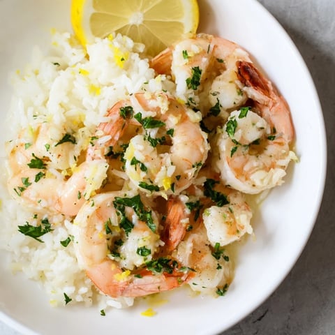 Golden garlic butter shrimp rice bowl, steaming and ready to eat, topped with fresh parsley.