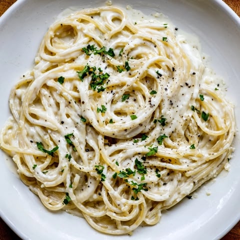 Thick, creamy Three-Cheese Spaghetti, perfectly coated and ready to eat, garnished with fresh parsley.