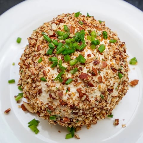 A beautifully arranged Classic Cheese Ball, coated in toasted pecans, ready to serve with crackers.