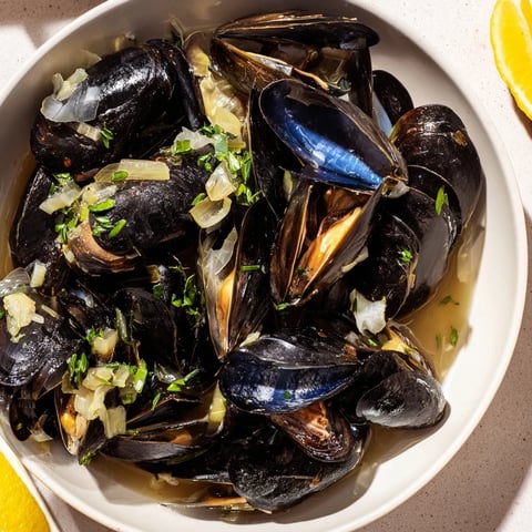 Steaming Belgian Moules Marinière with plump, open mussels and a rich, herb-infused broth.