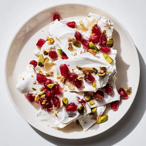 Cool and creamy frozen yogurt bark, layered with pomegranate and pistachio toppings, perfect dessert.