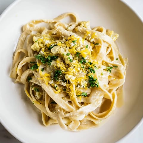 Steaming Creamy Roasted Cauliflower Garlic Pasta, topped with fresh herbs and a sprinkle of parmesan.