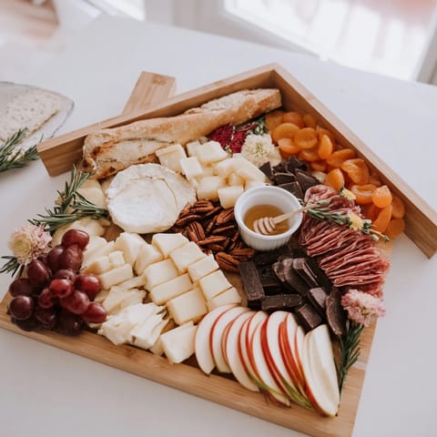 This Sweet Home Charcuterie Board offers a cozy assortment, featuring honey drizzled over cheeses and fruits.