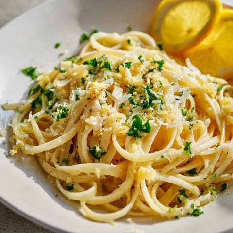Steaming plate of garlic butter linguine, ready to be served, topped with fresh parsley and parmesan.