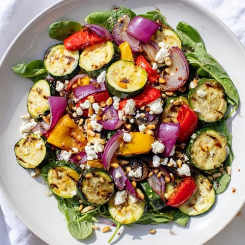 A beautiful bowl of roasted vegetable salad, featuring glistening tomatoes and caramelized bell peppers.