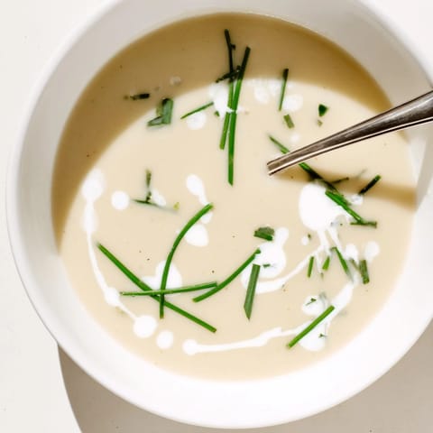 Warm Celery Root Bisque in a rustic bowl with a drizzle of truffle oil and crusty bread.