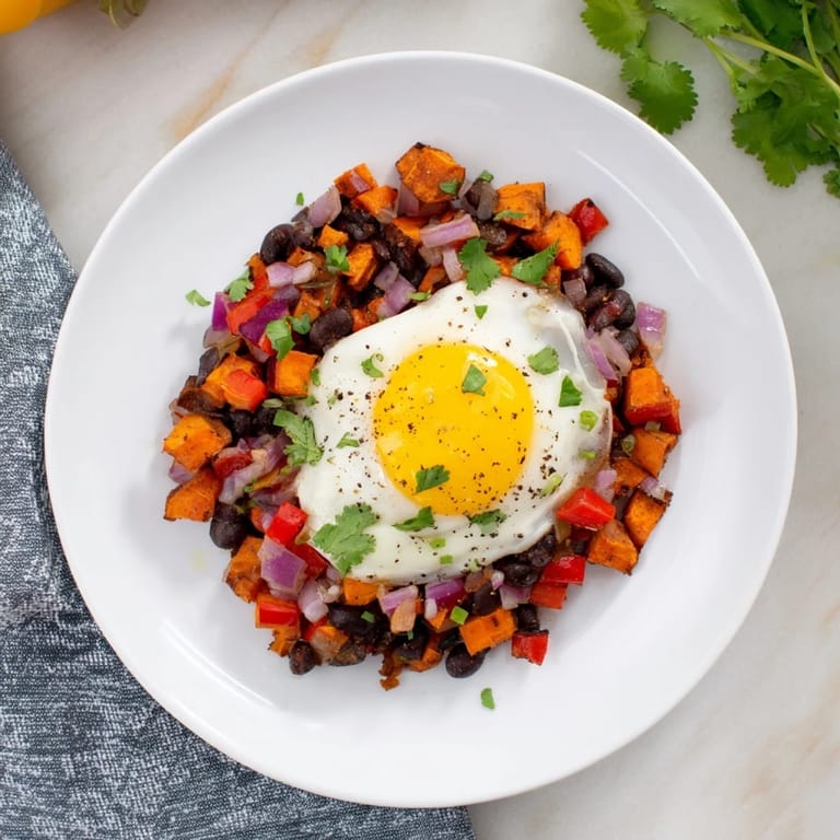 Flavorful Sweet Potato & Black Bean Breakfast Hash with vibrant cilantro and a runny egg yolk.