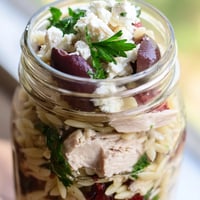 A vibrant Greek Pasta Chicken Salad Jar layered with orzo, juicy chicken, and crisp vegetables topped with feta.