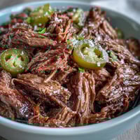 Shredded Slow Cooker Mississippi-Style Ranch Beef piled onto a toasted sandwich roll with melted provolone and pepperoncini.