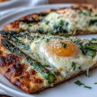 Crispy flatbread with asparagus and a perfectly baked egg, topped with parmesan and fresh herbs.